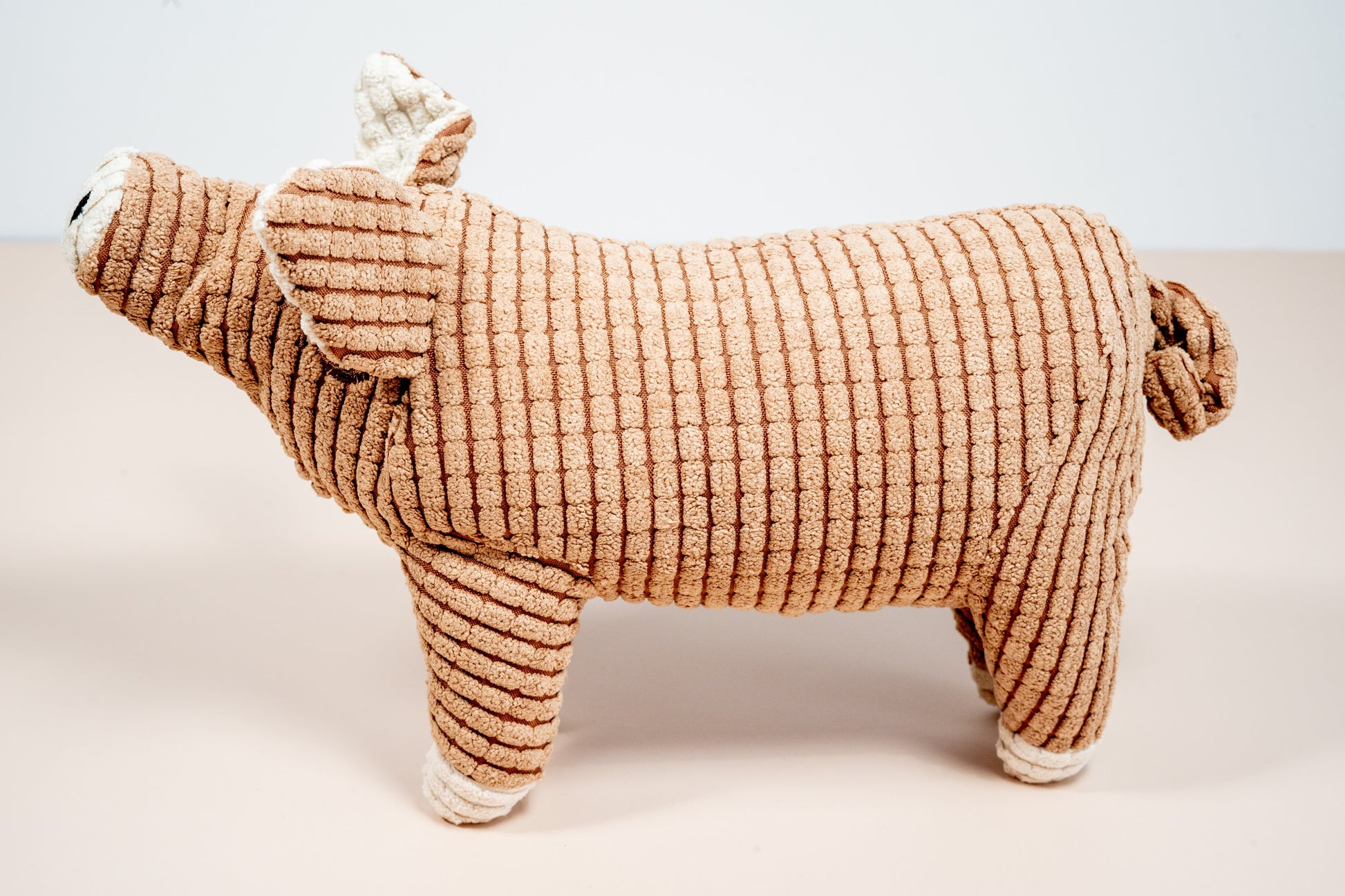 Side view brown pig shaped plush dog toy. | Jouet pour chien en peluche en forme de cochon marron vue latérale.