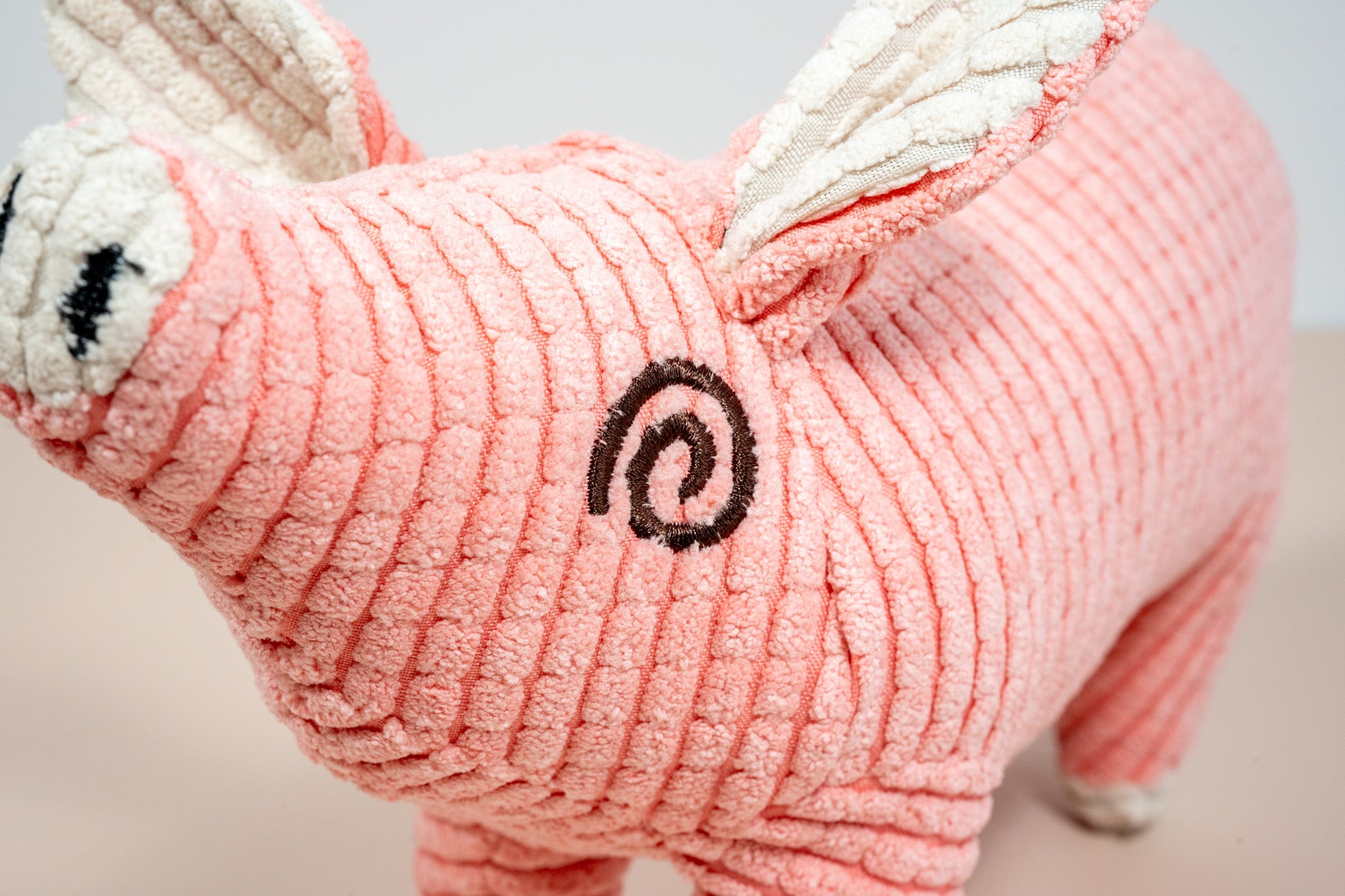Close-up view of pink pig plush dog toy. | Vue rapprochée du jouet pour chien en peluche cochon rose.