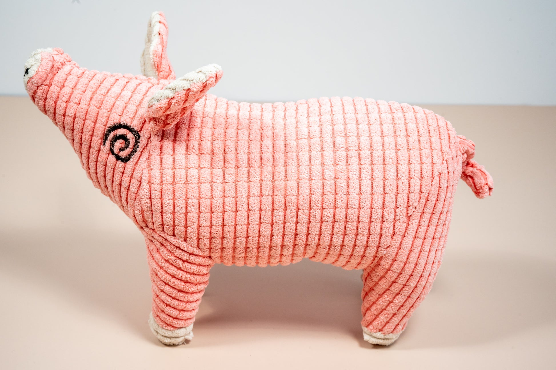Side view pink pig shaped plush dog toy. | Jouet pour chien en peluche en forme de cochon rose vue latérale.