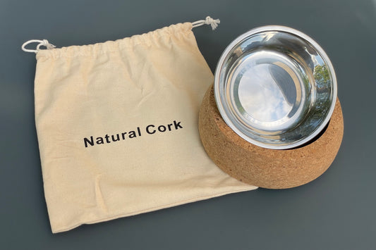 Stainless steel dog bowl with cork base and 'Natural Cork' drawstring bag on a gray background.|Gamelle pour chien en acier inoxydable avec base en liège et sac à cordon « Natural Cork » sur fond gris.
