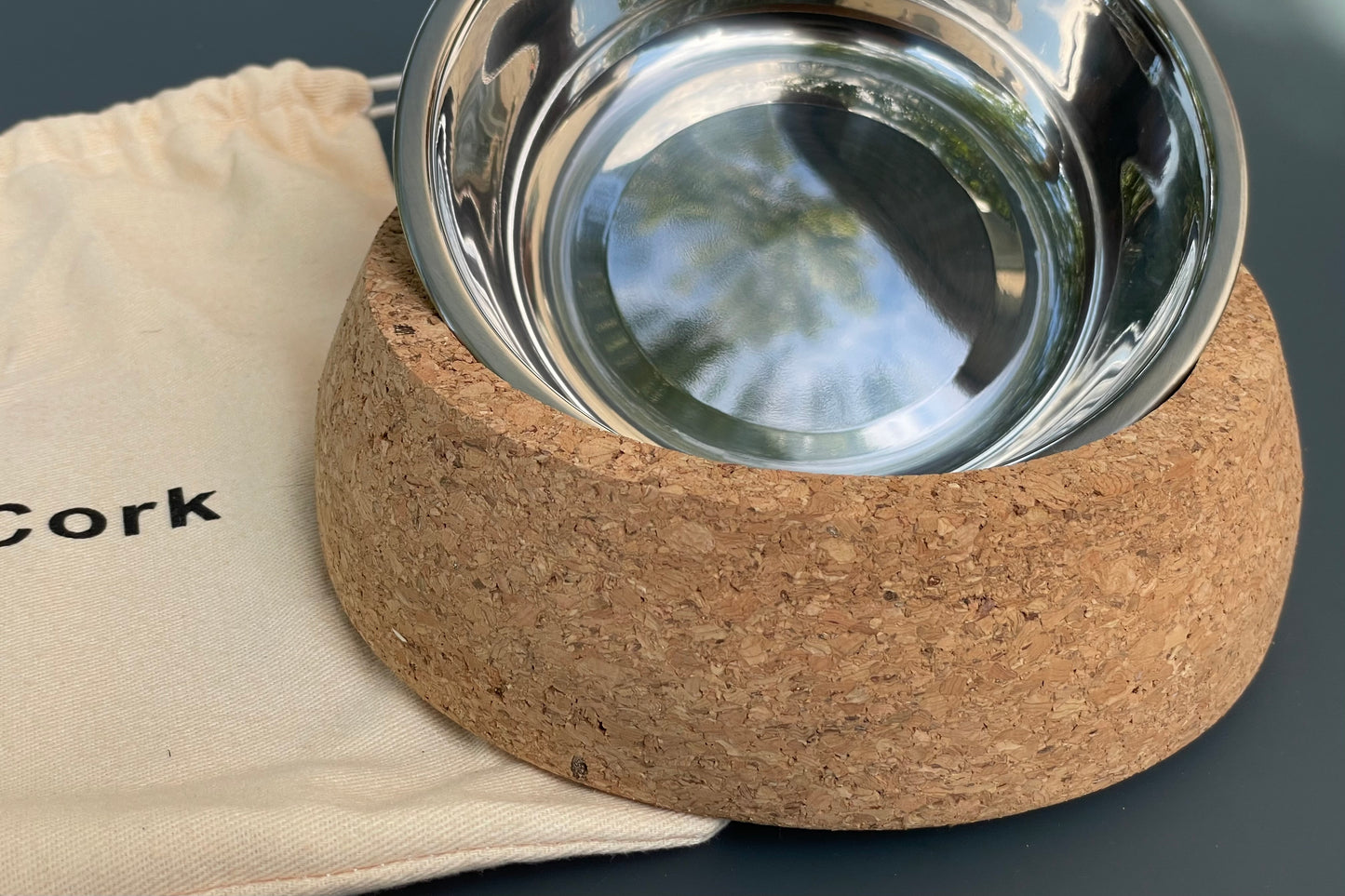 Cork base with a metal bowl for pets on a gray background.