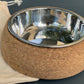 Cork dog bowl with a metal interior on a gray background.