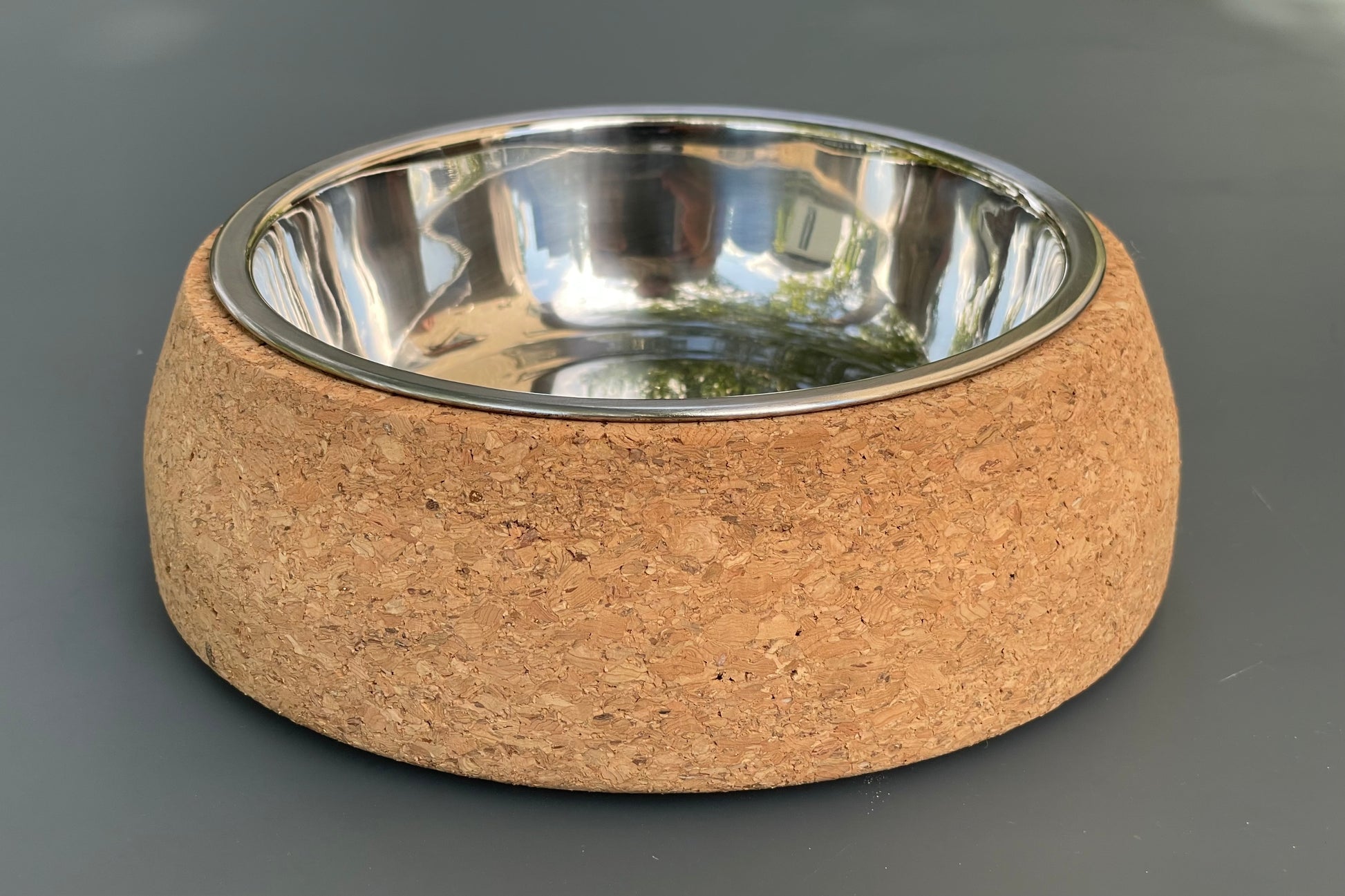 Cork dog bowl with a metal interior on a gray background.