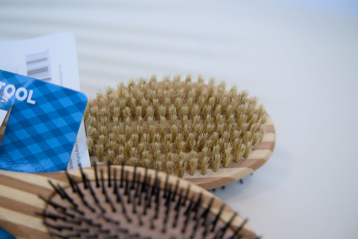 Two wooden pet brushes with bristle heads on a white surface.