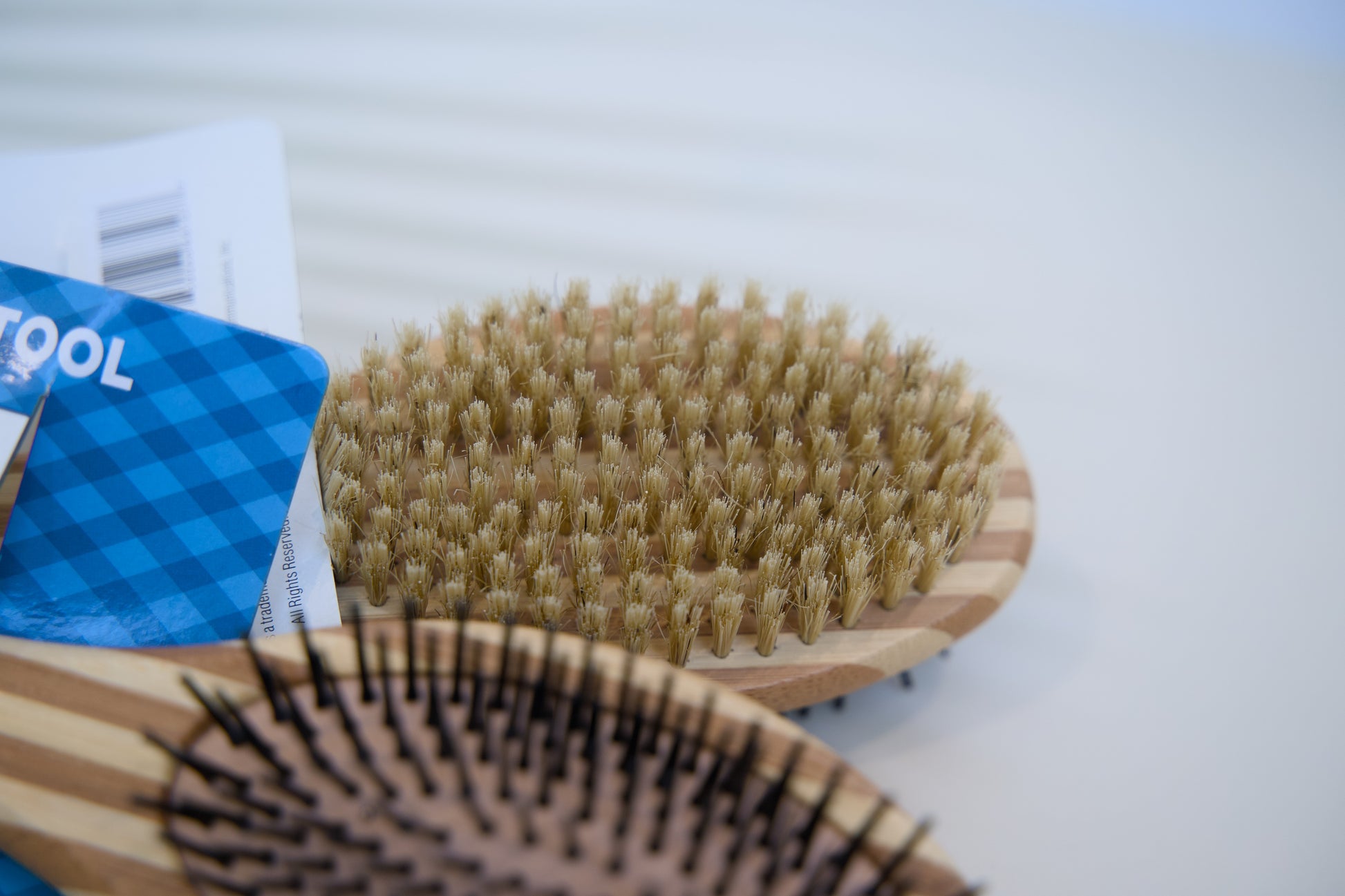 Two wooden pet brushes with bristle heads on a white surface.
