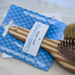 Wooden pet grooming brush with County Living tag on a blue card.