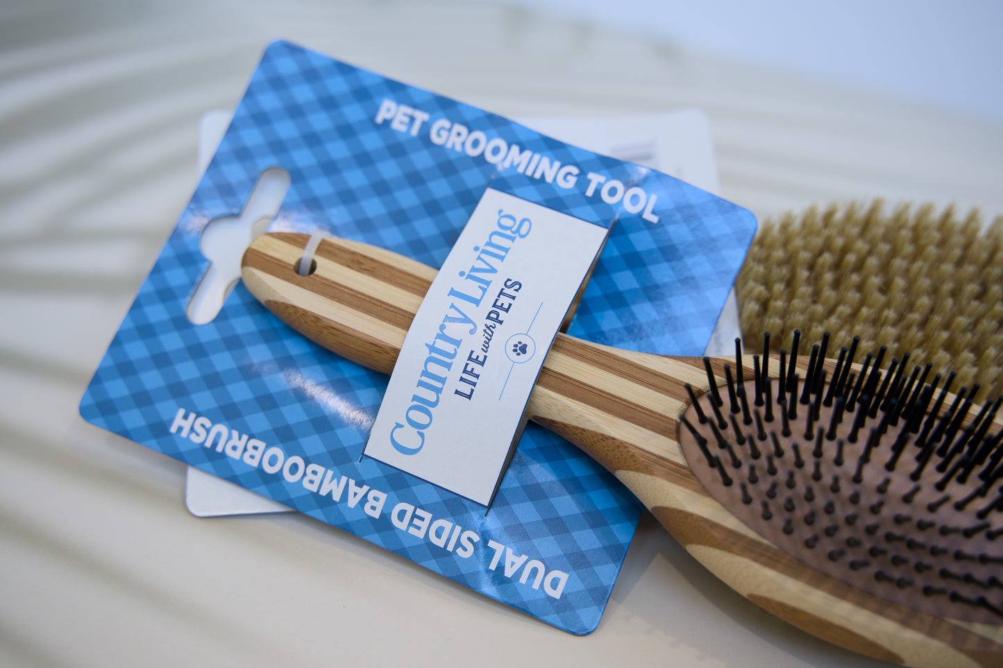 Wooden pet grooming brush with County Living tag on a blue card.