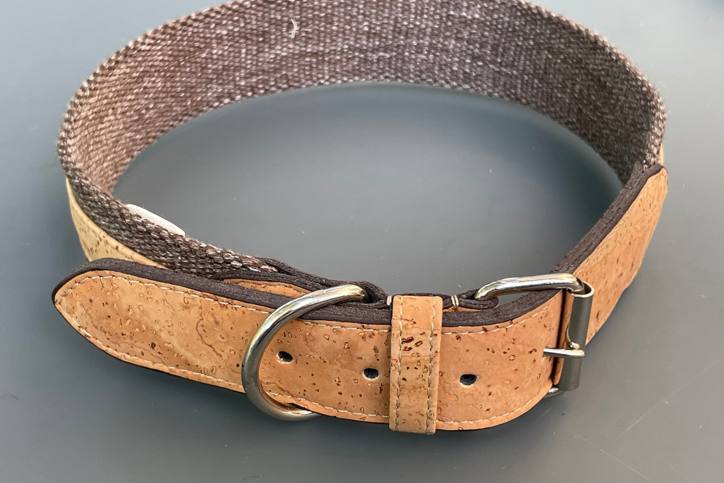 Dog collar with cork strap and metal buckle on a gray background.