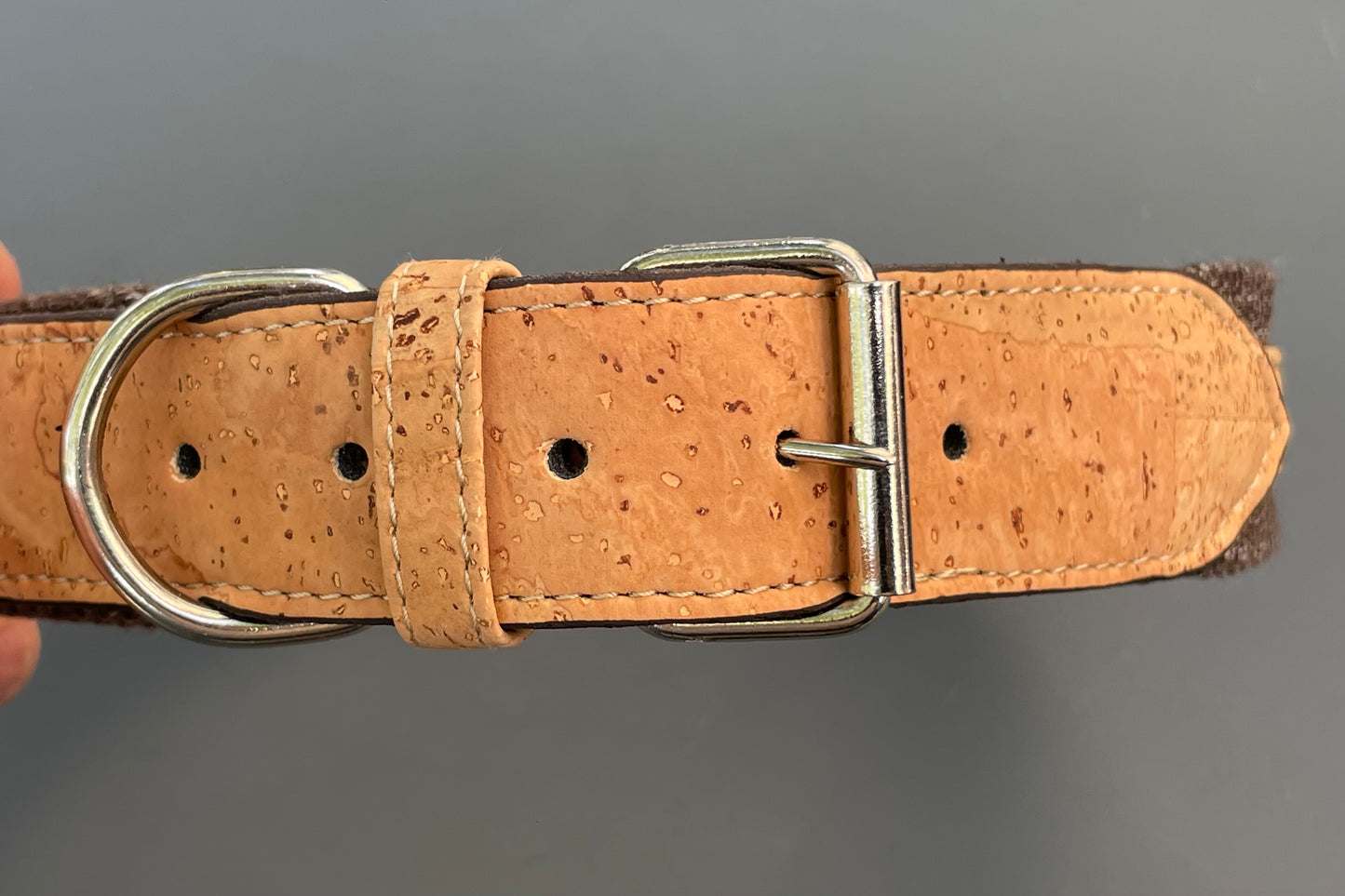 Brown cork dog collar with metal buckle on a gray background.