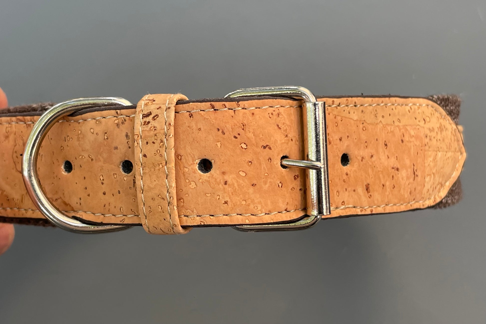 Brown cork dog collar with metal buckle on a gray background.
