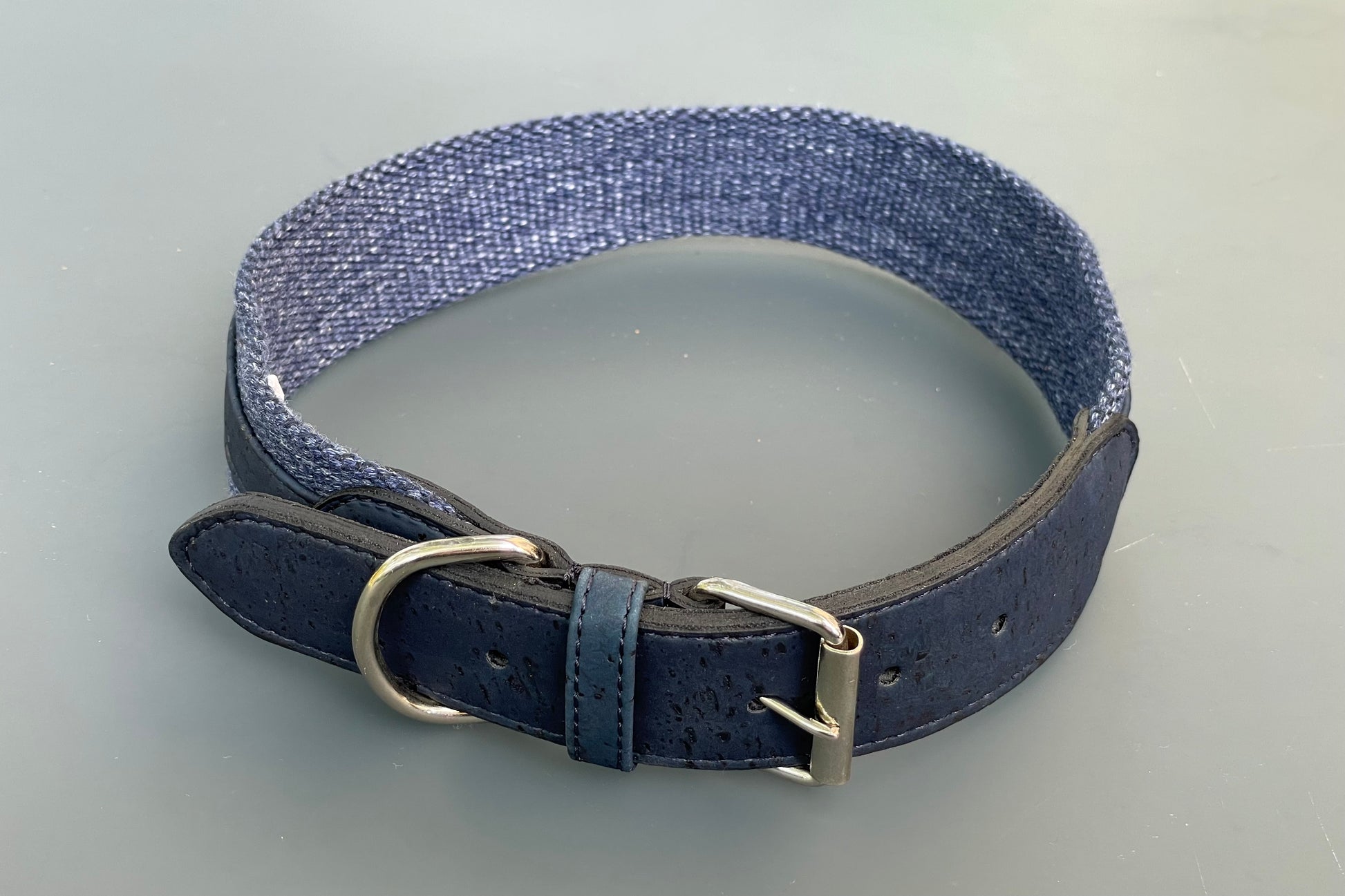 Blue dyed cork dog collar with a metal buckle on a gray background.