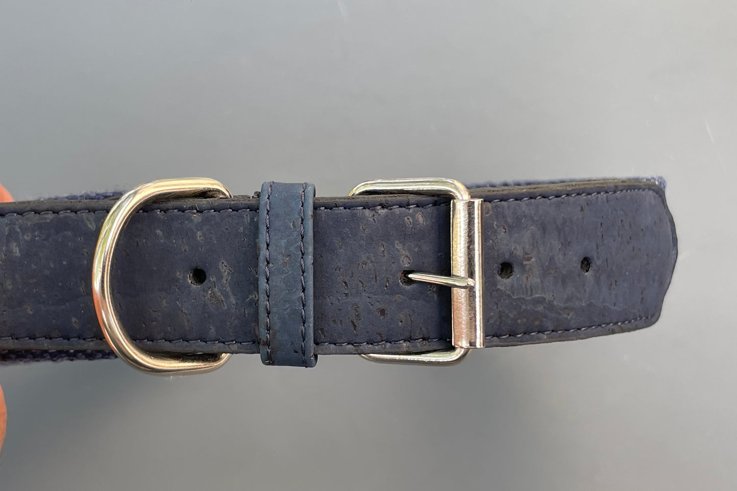 Navy blue cork dog collar with brass buckle on a gray background.