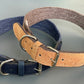 Two dog collars, one blue and one brown with cork texture, on a reflective surface.