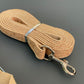 Laisse pour chien beige avec clip en métal sur fond gris.
