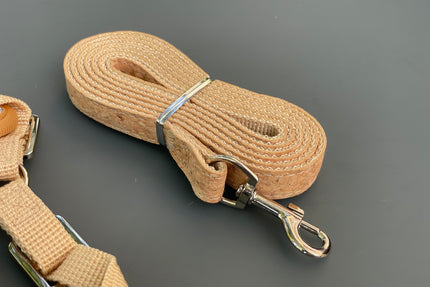 Beige dog leash with metal clip on a gray background.