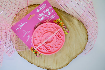 Jouet pour chien rose, tapis d'alimentation lente et de léchage, posé sur une surface en bois.