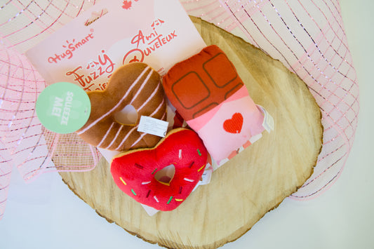 Donut-shaped dog toys with a heart design on a wooden surface.|Jouets pour chiens en forme de beignet avec un motif de cœur, posés sur une surface en bois.