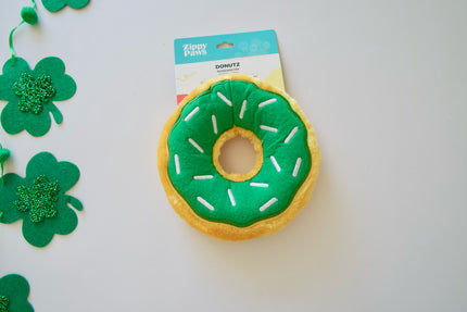 Green and yellow donut-shaped pet toy with shamrock decorations on a white background.