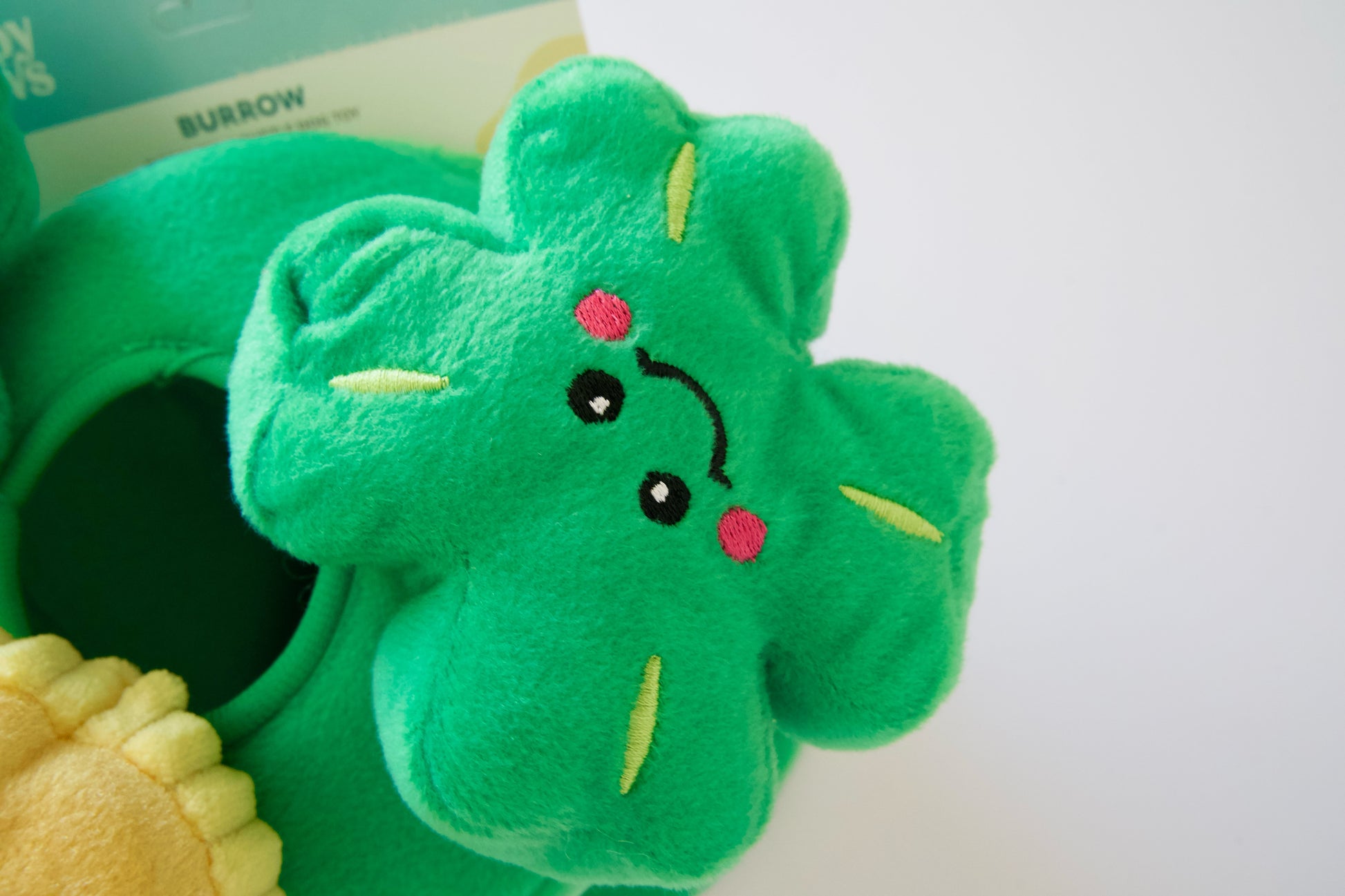 Clover plush dog toy with a face on a white background.