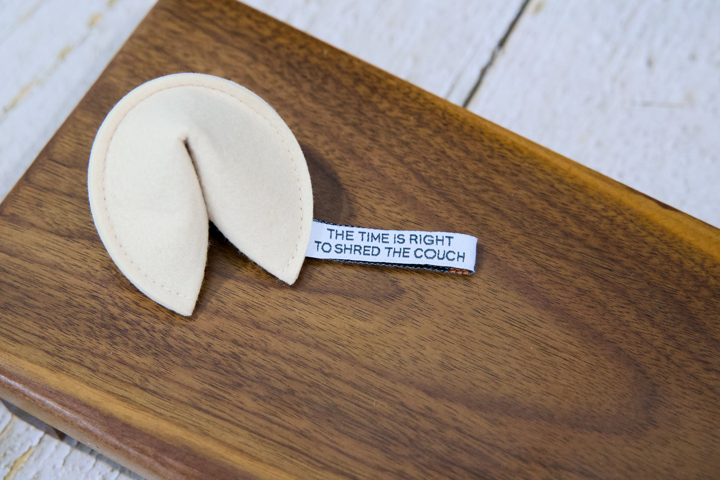 A fortune cookie cat toy with catnip and a tag that reads THE TIME IS RIGHT TO SHRED THE COUCH.