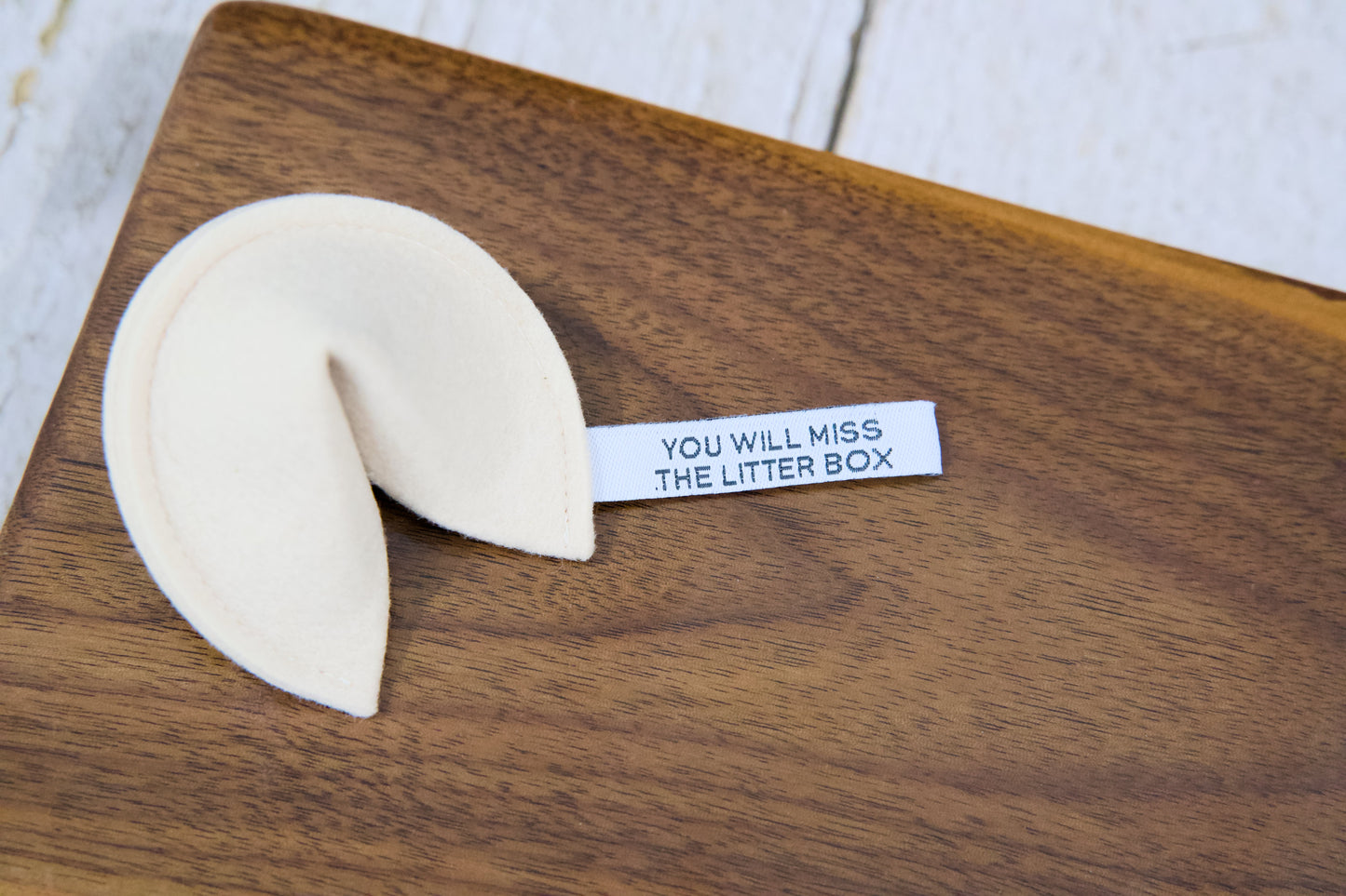 A fortune cookie cat toy with catnip and a tag that reads YOU WILL MISS THE LITTER BOX.