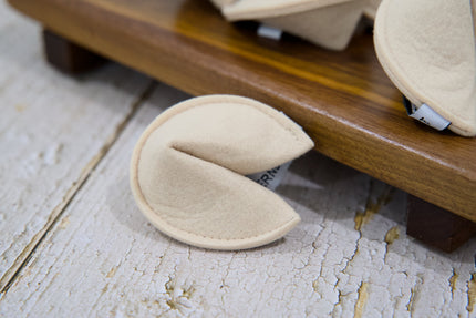 Close-up of a felt cat toy shaped like a fortune cookie.