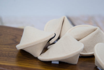 A close-up of fortune cookies felt pet toys arranged on a wooden surface.
