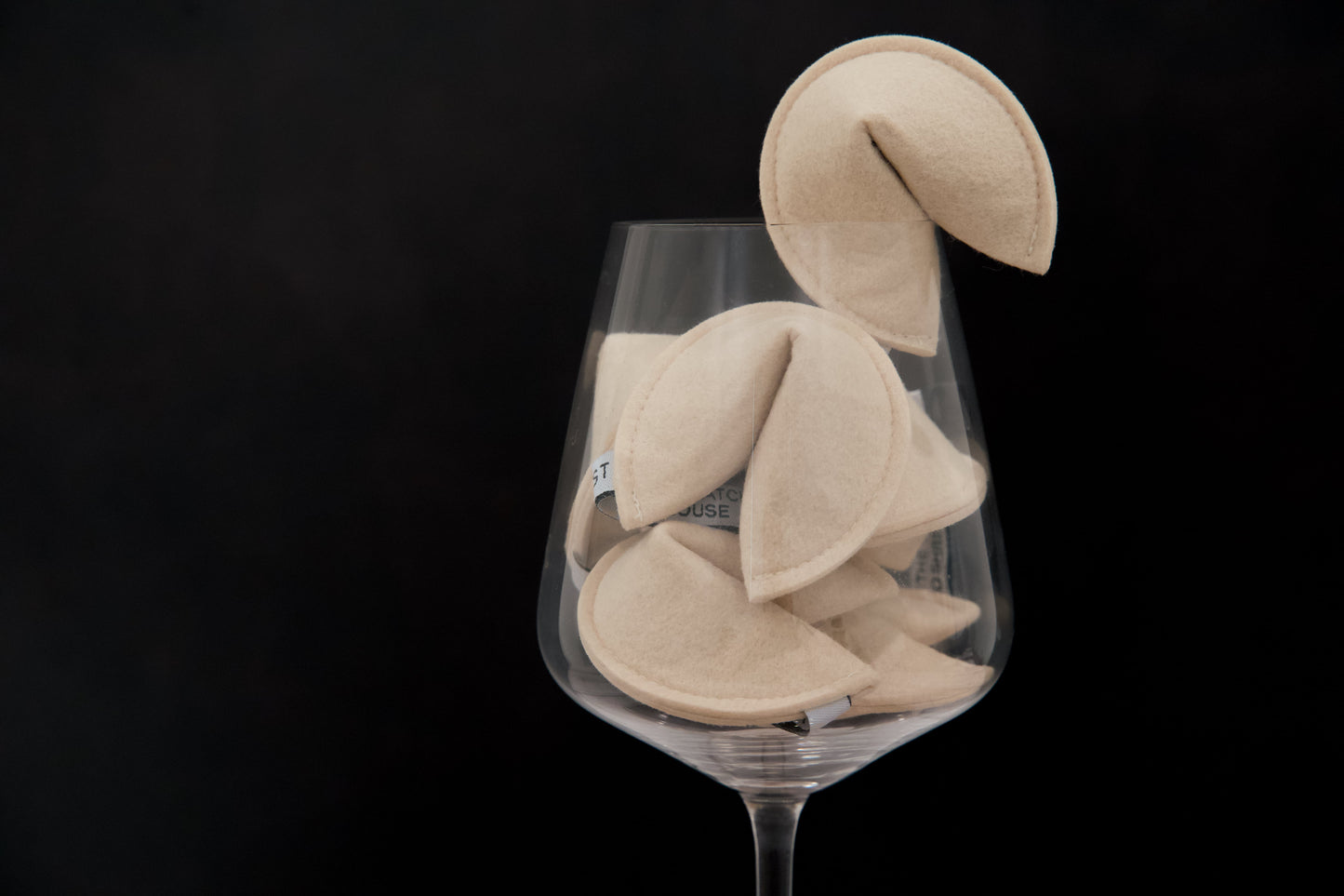 Catnip-filled cat toys shaped like fortune cookies, in a wine glass.
