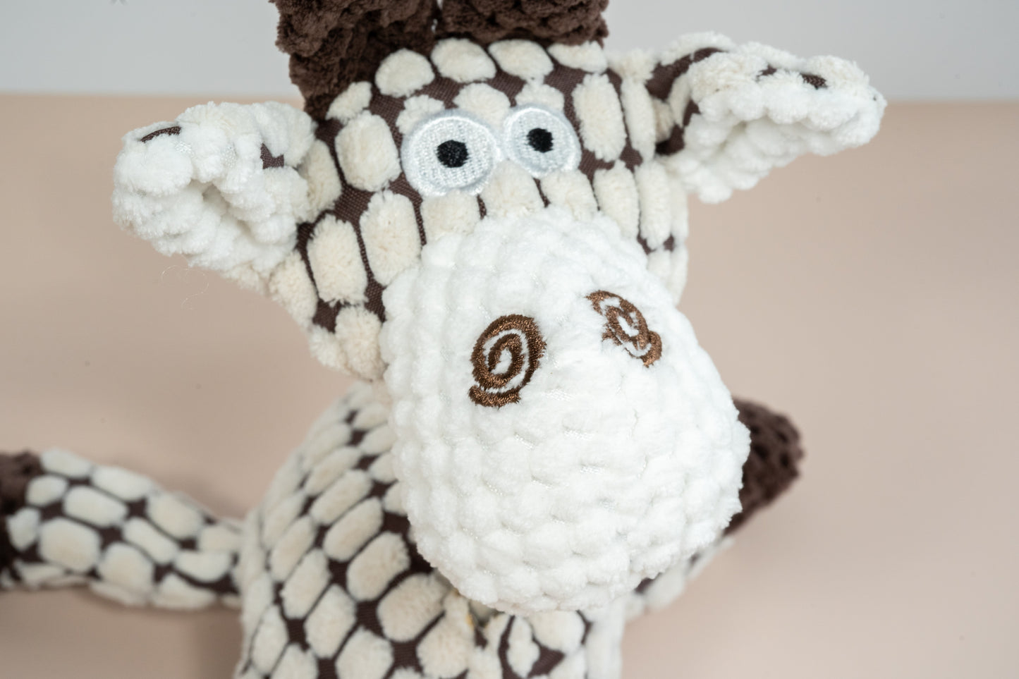 Close-up view of giraffe plush face with rope neck.