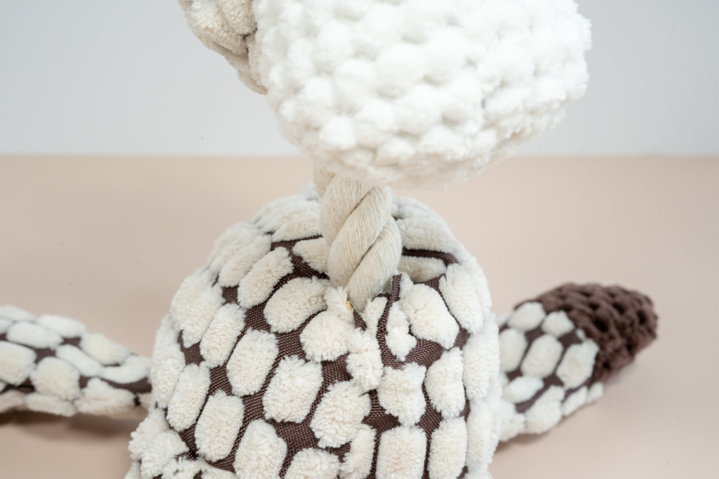 Close-up view of the rope neck of the giraffe dog plush.