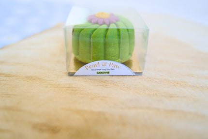 Des croquettes pour chiens au goût de sardine et de truffe, présentées dans un emballage transparent sur une surface en bois.