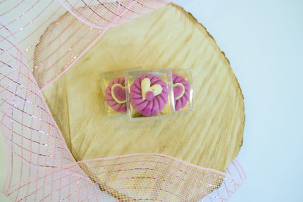 Pink dog cookies in clear cases on a decorative background.