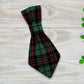 Plaid dog tie on a wooden surface with clover leaves.