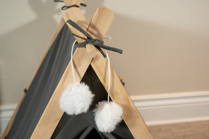 Vue rapprochée des pompons décoratifs blancs super doux de la tente pour animaux gris foncé.