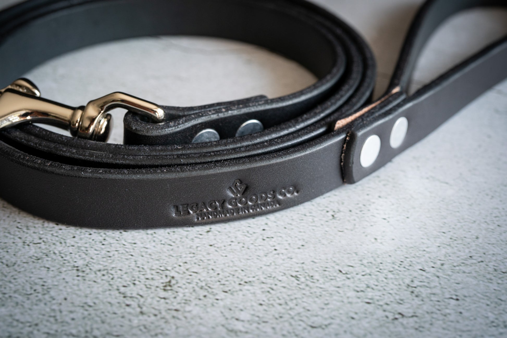 Black leather pet leash with company name printed. | Laisse pour animal en cuir noir avec nom de l'entreprise Legacy Goods Co étampé.