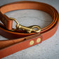 Brown leather dog leash with copper-colored metal clip.