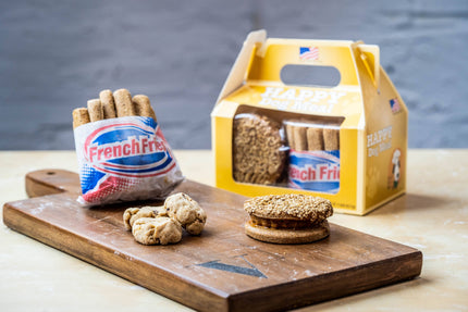 Menu Joyeux Festin pour chien avec frites, un burger et des cookies, sur une planche en bois.