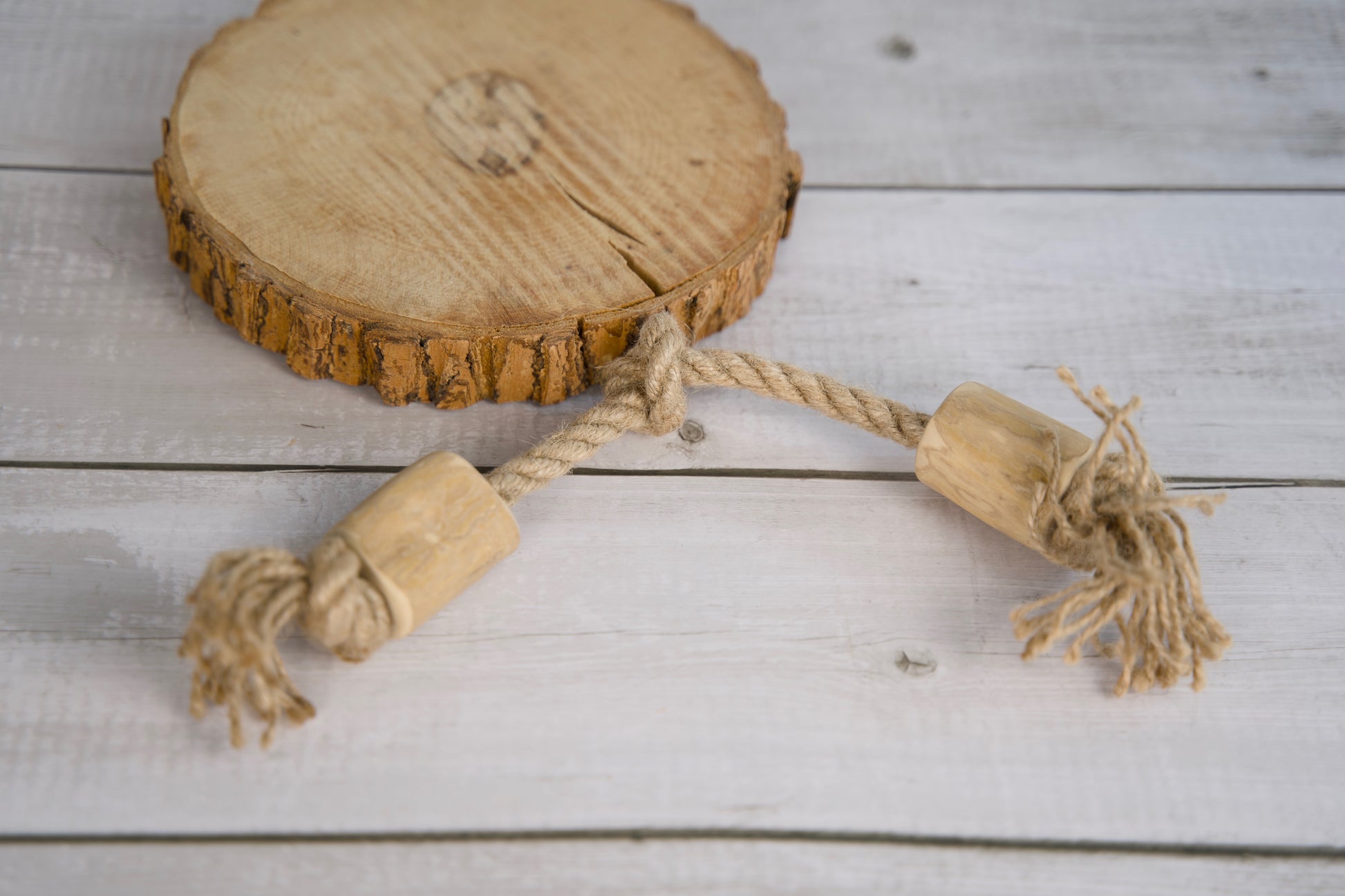 Wooden chew and hemp rope dog toy with rope on a wooden surface.