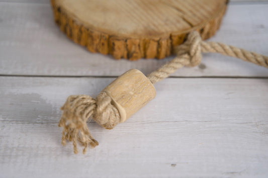 Wooden knot with rope dog toy on a wooden surface.|Jouet pour chien en bois et corde, posé sur une surface en bois.