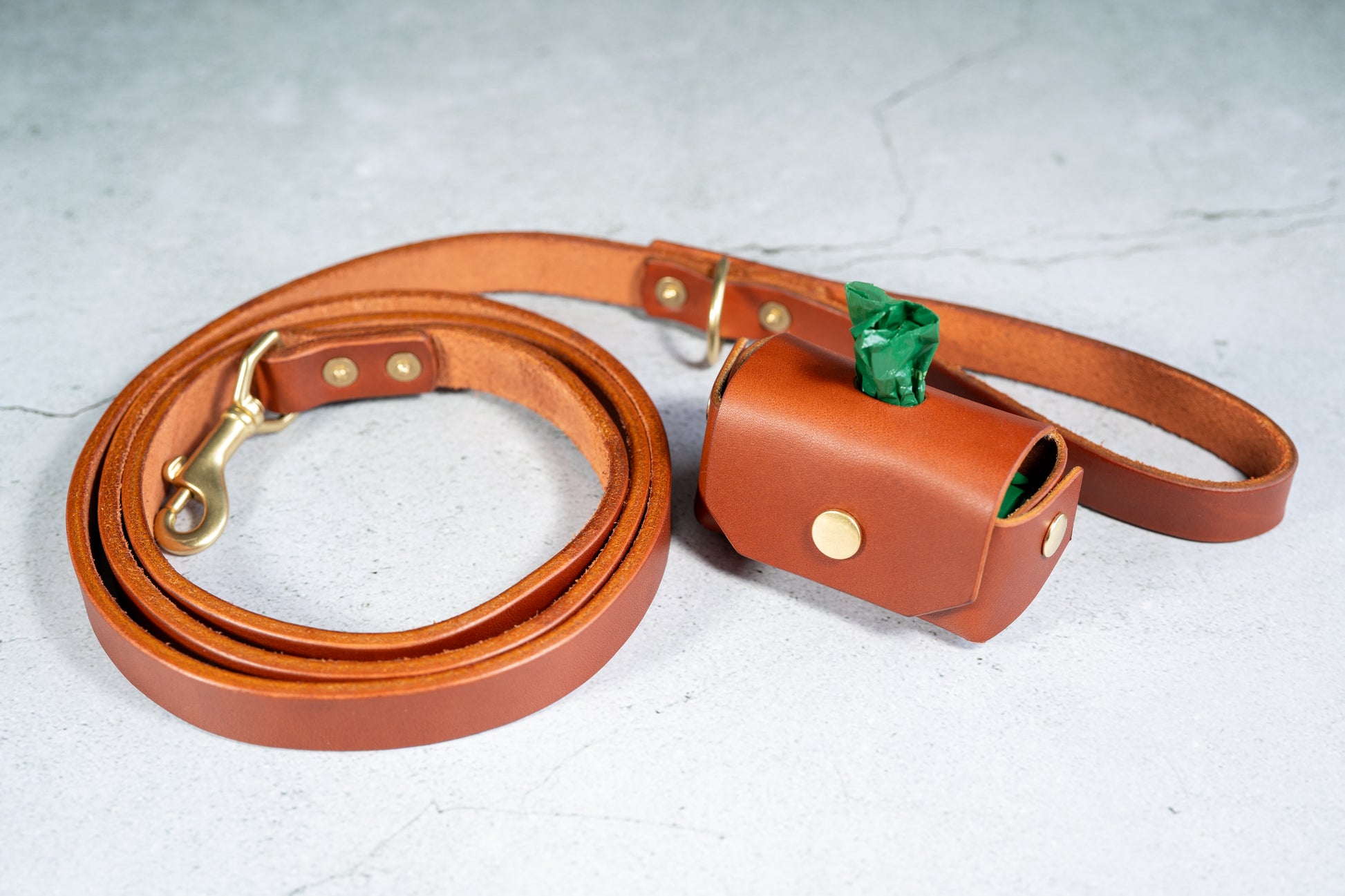 High quality handmade chestnut leather dog leash and poop bag holder set. | Ensemble de laisse et de porte-sac à crottes en cuir couleur châtaigne fait à la main de haute qualité.