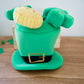 Green leprechaun hat dog interactive toy with a face on a wooden surface.