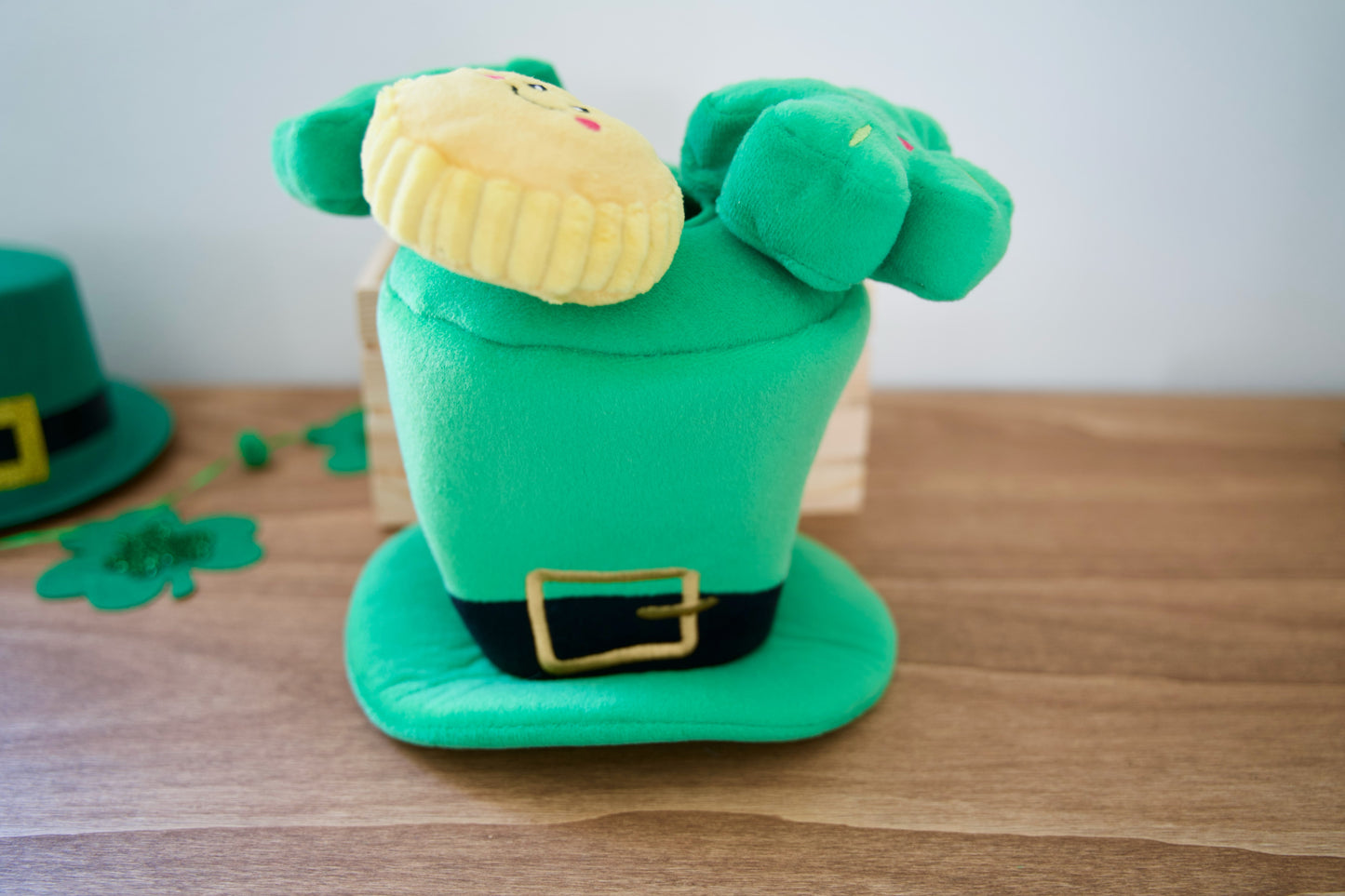 Green leprechaun hat dog interactive toy with a face on a wooden surface.