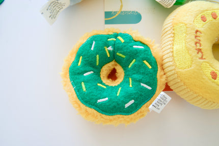 Dog toy resembling a donut with green icing and yellow sprinkles on a white background.