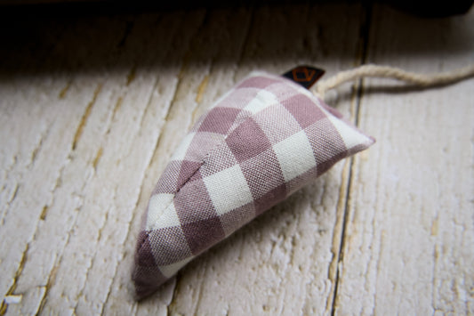 A modern cat toy mouse filled with catnip resting on a rustic white wooden surface.|Une souris-jouet moderne pour chat, remplie d'herbe à chat, posée sur une surface en bois blanc rustique.