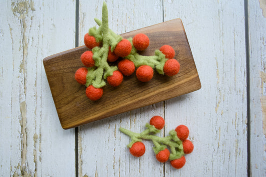 Felted vine on tomato, dog and cat toys on a wooden board.|Tige de vigne feutrée sur une tomate, jouets pour chiens et chats sur une planche en bois.