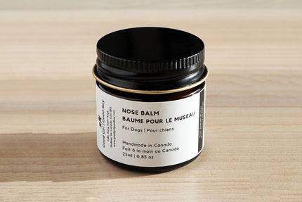 Pot de baume nasal pour chiens sur une surface en bois.