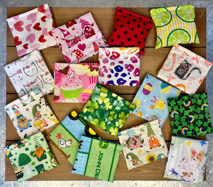 Collection de jouets pour chats en forme de carrés de tissu colorés avec différents motifs, posés sur une surface en bois.