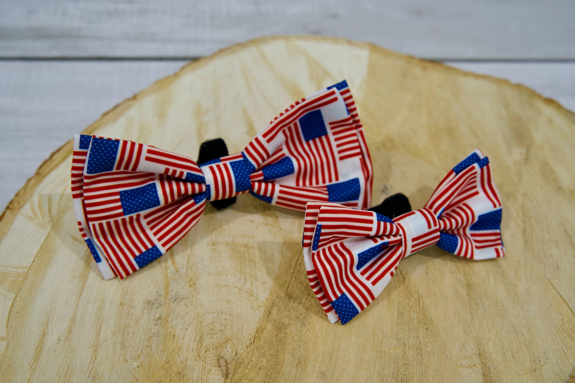 Deux nœuds papillon pour animaux aux motifs du drapeau américain, posés sur une surface en bois.