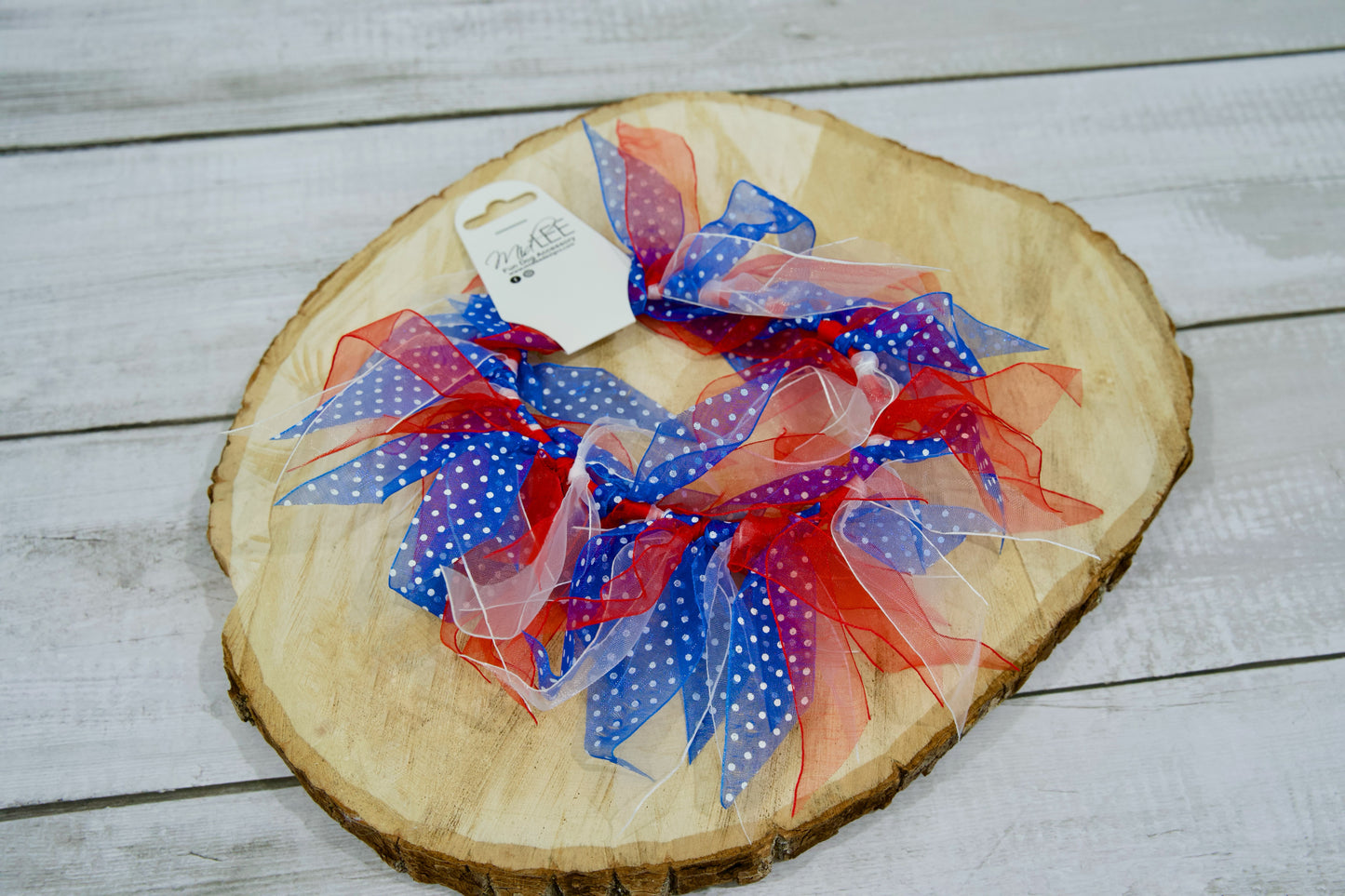 Collier pour animal avec rubans à pois rouges, blancs et bleus, posé sur une surface en bois.