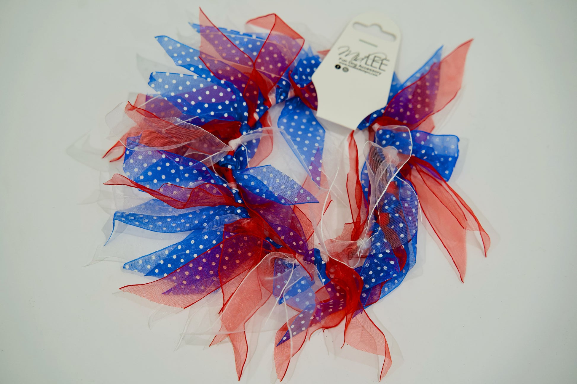Collier décoratif pour animal avec des rubans rouges, blancs et bleus sur fond blanc.